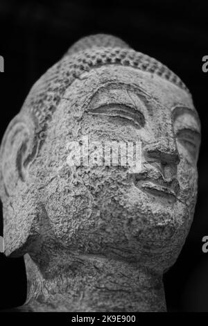 Budha Gesicht aus der Nähe. Nahaufnahme eines buddha-Kopfes auf schwarzem Hintergrund. Bhuddha Statue aus Stein. Niemand, Reisefoto Stockfoto