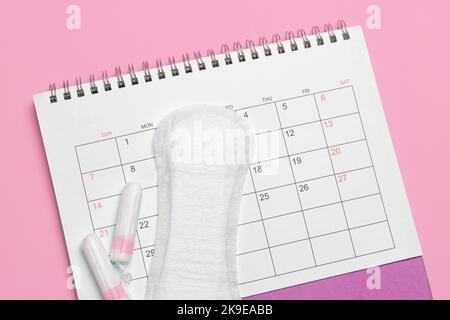 Menstruationskalender. Kalender mit Pads und Tampons auf rosa Hintergrund. Stockfoto