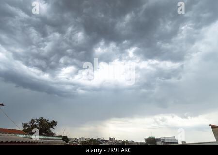 Wolkiger Himmel, der mehrere Wolken mit der Stadt am Horizont bildet. Stockfoto