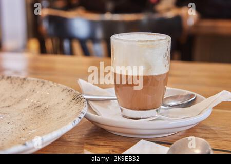Cappuccino-Kaffee in transparentem Glas auf Teller in einem café im mediterranen Stil Stockfoto