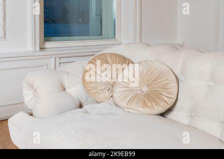 Luxuriöse und klassische Kissen auf beigefarbenem Sofa. Dekorative beigefarbene Wildlederkissen auf der Couch. Stockfoto