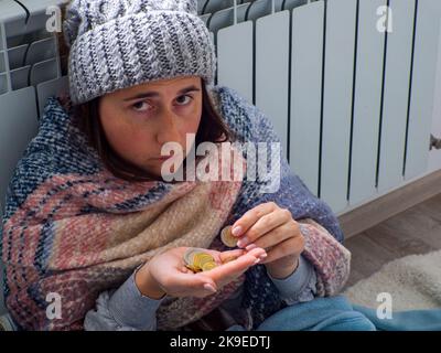 Frau, die in der Nähe der Batterie sitzt und Euromünzen zählt Stockfoto