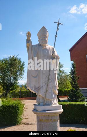 Eine aus weißem Stein geschnitzte Marmorstatue von Papst Johannes Paul II. Vor der katholischen Kirche, der Kathedrale unserer Lieben Frau von der ewigen Hilfe. In Astana, Nursultan, Stockfoto