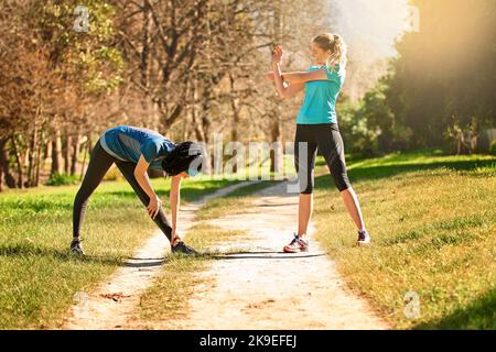 Stretching in der Natur. Zwei sportliche junge Frauen trainieren in der Natur. Stockfoto