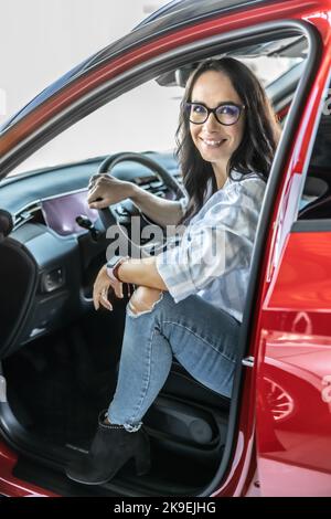 Ein zufriedener Kunde sitzt kurz vor dem Kauf in einem neuen roten Auto. Stockfoto