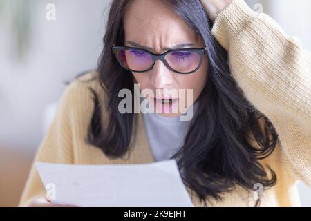 Frau schockiert über die Informationen, die sie aus dem Brief liest. Stockfoto