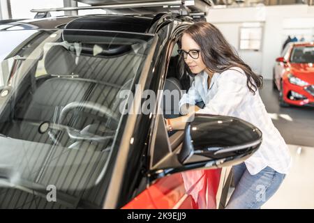 Ein junger Kunde nutzt die Inspektion eines Neuwagens im Laden. Stockfoto