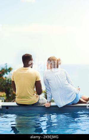 Kommt näher, ich möchte Euch ein Geheimnis erzählen. Rückansicht eines jungen Paares, das zusammen Getränke genießt und sich im Urlaub im Freien entspannt. Stockfoto