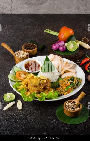 Ayam Goreng Lengkuas oder Gewürze gebratenes Huhn ist ein traditionelles indonesisches gebratenes Huhn mit frischen Kräutern, Gemüse und Chilisauce, serviert in weißen pl Stockfoto