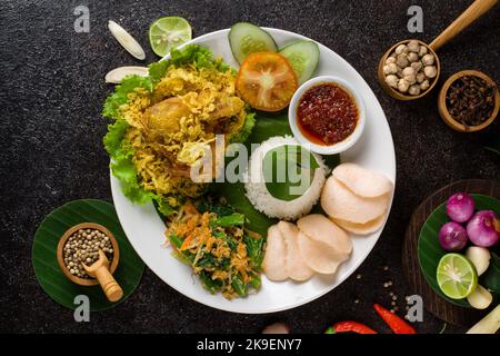 Ayam Goreng Lengkuas oder Gewürze gebratenes Huhn ist ein traditionelles indonesisches gebratenes Huhn mit frischen Kräutern, Gemüse und Chilisauce, serviert in weißen pl Stockfoto