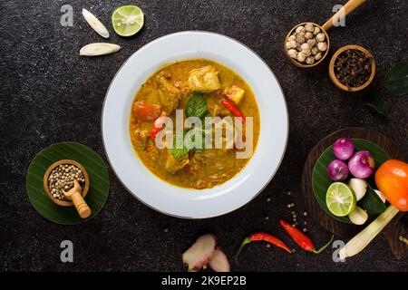 Gelber Fisch oder Gulai ikan mit Tilapia-Fisch gewürzt mit frischen Kräutern und Gewürzen Stockfoto