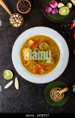 Gelber Fisch oder Gulai ikan mit Tilapia-Fisch gewürzt mit frischen Kräutern und Gewürzen Stockfoto