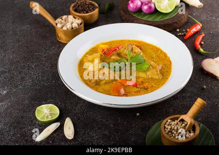 Gelber Fisch oder Gulai ikan mit Tilapia-Fisch gewürzt mit frischen Kräutern und Gewürzen Stockfoto