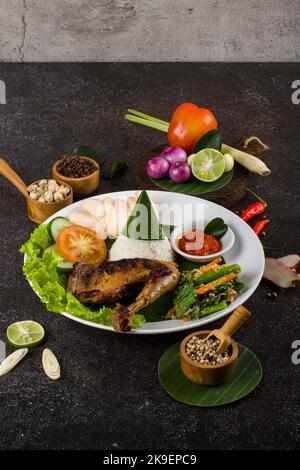 Ayam Bakar oder gebratenes Huhn mit Kräutern und Gewürzen aus Indonesien, serviert auf einem weißen ovalen Teller Stockfoto