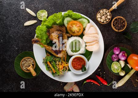 Ayam Bakar oder gebratenes Huhn mit Kräutern und Gewürzen aus Indonesien, serviert auf einem weißen ovalen Teller Stockfoto