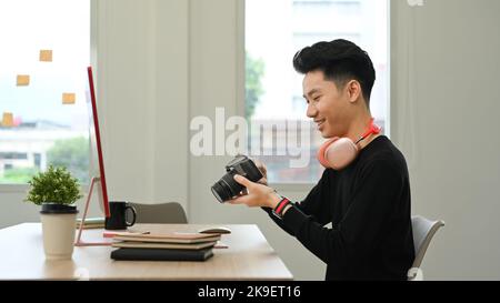 Seitenansicht eines hübschen männlichen Fotografen, der in einem hellen, modernen Kreativstudio arbeitet Stockfoto