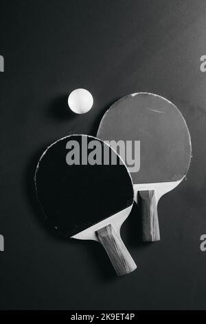 Zwei Tischtennisschläger und ein Ball befinden sich auf dem grünen Spieltisch Stockfoto