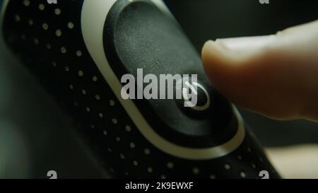 Ein-/aus-Taste in Nahaufnahme, ein Finger, der zum ein-/aus-Schalter drückt, Energie- und Technologiekonzept Stockfoto