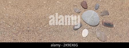 Steine in Form von Sonne, Sandstein am Sandstrand, heißer Sand, Urlaubszeit Stockfoto