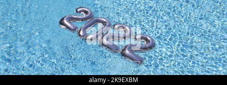Silberne Foliennummern schweben auf blauem, sauberem Poolwasser, festliches Dekor Stockfoto