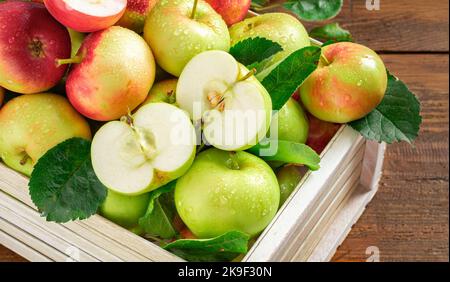 Ernten Sie frische rote und grüne Äpfel in einer Holzkiste auf einem Holztisch aus der Nähe von oben Stockfoto