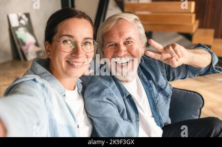 Glücklicher Großvater mit Enkelin, die ein Selfie zur Erinnerung macht und zu Hause sitzt Stockfoto