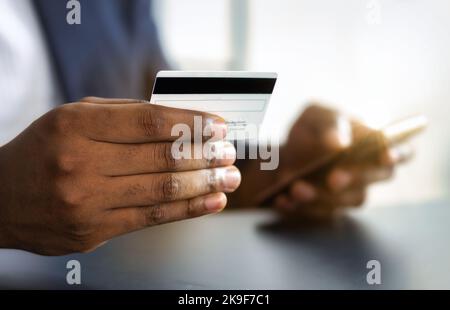Online-Banking, Rechnungszahlung. Kreditkarte in der Hand afroamerikanischer Mann Nahaufnahme. Speicherplatz kopieren Stockfoto