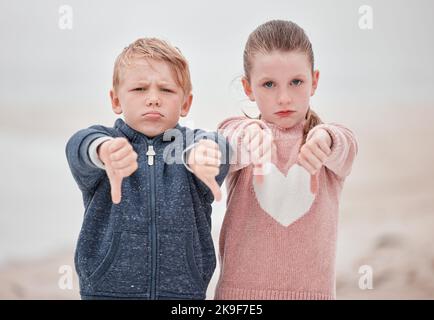 Trauriges Kinderporträt, Daumen nach unten oder draußen mit Nachrichten über negative Ukraine-Probleme, um gegen den Krieg zu protestieren. Weiße Geschwister stimmen Nein, zornige Emoji in Kälte Stockfoto