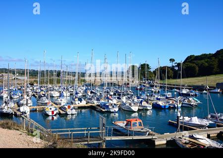 Brücke über den Fluss Axe mit kleinen Fischerbooten und Yachten im Vordergrund und die Landschaft von Devon im Hintergrund, Axmouth, Devon, UK. Stockfoto