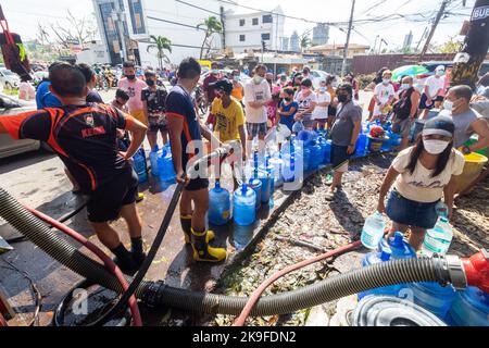 Mitglieder des Bureau of Fire Protection, die den Bewohnern Trinkwasser nach einer Wasserknappheit durch den Taifun Rai in Cebu, Philippinen, zur Verfügung stellen Stockfoto