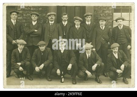 Ursprüngliche Postkarte aus dem frühen 20. Jahrhundert von Männern der Arbeiterklasse außerhalb eines Pubs, einige breite und einige dünnere Kragen so um 1912, viele flache Kappen, Lookalikes. Es gibt eine Flasche Bier neben einem Mann, also ist es ein Junggesellenabschied, Arbeit tun, Beförderung, Abschluss Lehre, Geburtstagsfeier, Neuer Vater. Wer weiß! GROSSBRITANNIEN Stockfoto