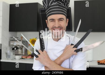 Koch hält ein paar Messer in der Hand Stockfoto