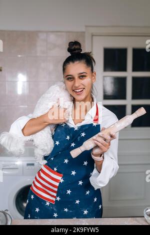 Fröhliche Frau mit einem Nudelholz und einem weißen maltesischen Hund Stockfoto