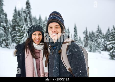 Es ist unsere Lieblingssaison des Jahres. Ein glückliches junges Paar, das sich beim draußen im Schnee amüsieren kann. Stockfoto