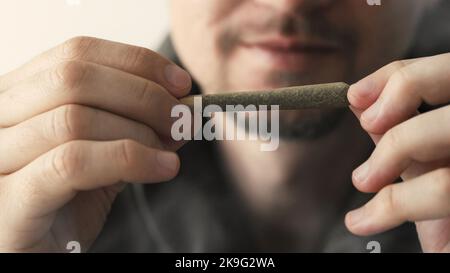 Junger Mann, der Marihuanagelenk in den Händen hält Stockfoto