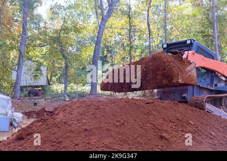 Auf der Baustelle wird ein kleiner Traktor verwendet, um den Boden zu bewegen, um Landschaft zu schaffen. Stockfoto