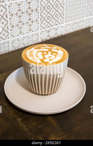Frisch gebrühter Latte in einer beigefarbenen Kaffeetasse aus Porzellan in einem Café Stockfoto