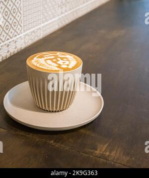 Frisch gebrühter Latte in einer beigefarbenen Kaffeetasse aus Porzellan in einem Café Stockfoto