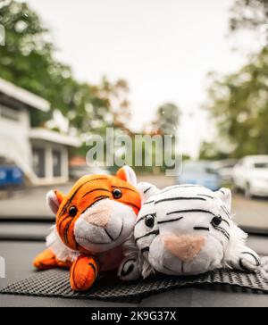 Orangefarbenes und weißes Plüschspielzeug für Tiger-Jungen auf dem Armaturenbrett des Autos Stockfoto