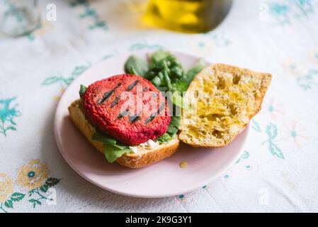 Roter hausgemachter veganer Rote Beete-Hamburger mit Salat und Brot auf dem Tisch. Rüben werden als Ersatz für Fleisch verwendet. Stockfoto