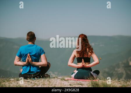 Yoga-Partner machen einige Yoga-Posen, während sie auf dem Berg sitzen Stockfoto