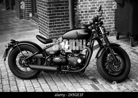 Eine Graustufenaufnahme eines geparkten Triumph Bonneville Bobber Motorrades Stockfoto