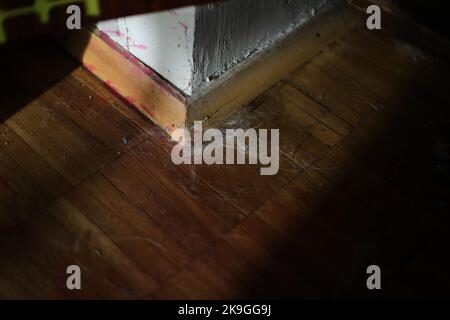 Ecke im Zimmer. Fußleiste auf dem Boden. Staub in der Ecke der Wand. Etage in der Wohnung. Stockfoto