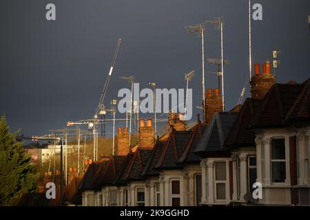 Eine urbane Szene aus TV-ariellen, Dächern, Kaminen und Reihenhäusern vor einem dunklen, stürmischen, grauen und bedrohlichen Himmel. Intensives Licht trägt zum Drama bei Stockfoto