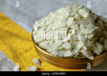 Nahaufnahme von rohem Poha/geschlagenem Reis/abgeflachter Reis in einem Messingbehälter Uruli/Gefäß Stockfoto