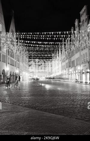 Eine lange Graustufen von Münsters Hauptmarkt in der Nacht und Menschen mit Fahrrädern in NRW Stockfoto