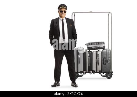 Reifer Mann in Uniform vor Koffern auf einem Wagen isoliert auf weißem Hintergrund Stockfoto