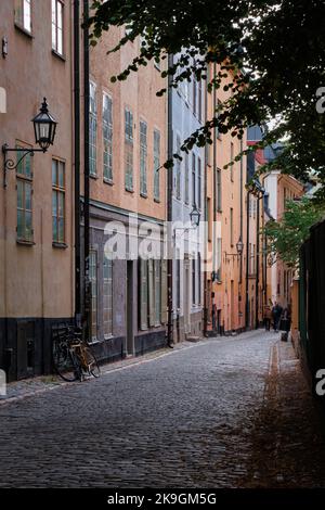 Stockholm, Schweden - 2022. September: Blick auf die farbenfrohe, schmale Altstadtstraße mit Kopfsteinpflasterstraße in Gamla Stan Stockfoto