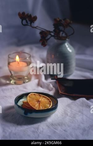 Vertikale Aufnahme eines Räucherstäbchens auf einer Keramikplatte bei Kerzenlicht für eine entspannte und gemütliche Herbststimmung Stockfoto