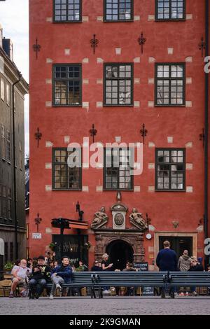 Stockholm, Schweden - 2022. September: Historisches rotes ikonisches Gebäude am Stortorget, einem kleinen öffentlichen Platz mit kleinem Café in Gamla Stan Stockfoto